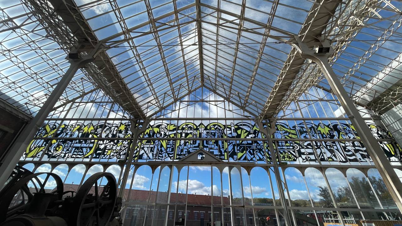 Frieze along the historic glazed machine hall seen from inside, above the old mining machinery, Lewarde